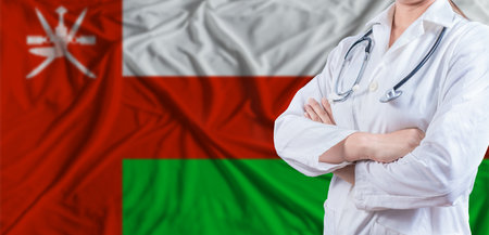 Doctor with crossed arms on Oman flag. Omani health and care concept. Female doctor on Oman flagの写真素材