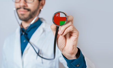 Doctor holding stethoscope with Oman flag. Oman health and care concept, Oman flag on stethoscopeの写真素材