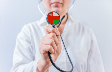 Female doctor holding stethoscope with Oman flag. National health system of Omanの写真素材