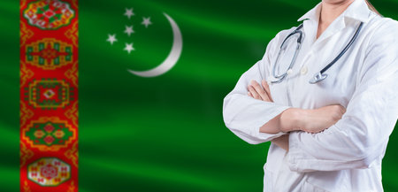 Doctor with crossed arms on Turkmenistan flag. Turkmen health and care concept. Female doctor on Turkmenistan flagの写真素材