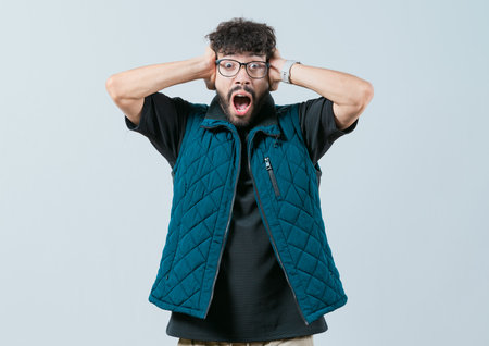 Young man holding his head isolated. Worried and alarmed man holding his head