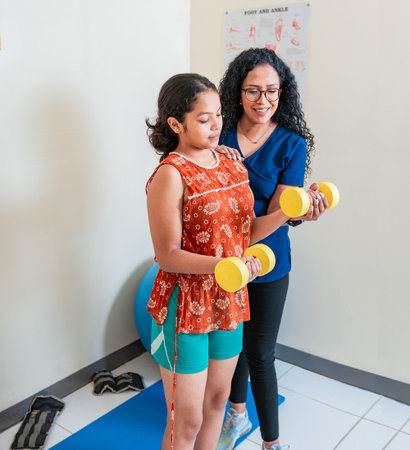 Physiotherapist helping patient with dumbbells on rehabilitation ball. Rehabilitation physiotherapy...