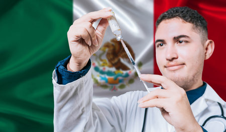 Doctor holding syringe on Mexico flag background. Medical professional holding syringe with Mexican flag in the backgroundの写真素材
