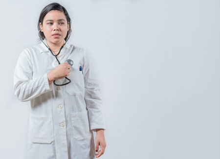 Asian Female Doctor Listening to Her Own Heartbeat with Stethoscope isolated. Young female doctor...