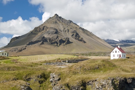 Farm and house at the foot of volcanic hill. In the background, the base of Snaefellsjokull volcano. The top of volcano is covered by clouds. Picture taken in Arnarstapi, Icelandのeditorial素材