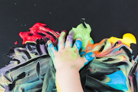 baby painting with colored paint with his handsの写真素材