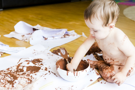 baby sitting painting with hands with chocolateの写真素材