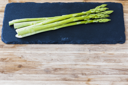 A bunch of green asparagus on a black panの写真素材