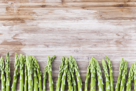 A bunch of green asparagus on wooden board with copy spaceの写真素材