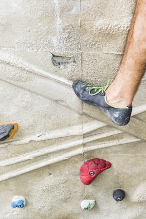 A Man practicing rock climbing on artificial wall indoors. Active lifestyle and bouldering concept.の写真素材