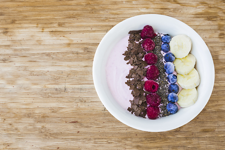 A Smoothie bowl with fresh berries, banana, chia seeds and chocolate for healthy vegan and vegetarian diet breakfastの写真素材