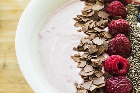 A Smoothie bowl with fresh berries, banana, chia seeds and chocolate for healthy vegan and vegetarian diet breakfastの写真素材