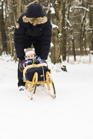 A baby sledding on snow in the forestの写真素材