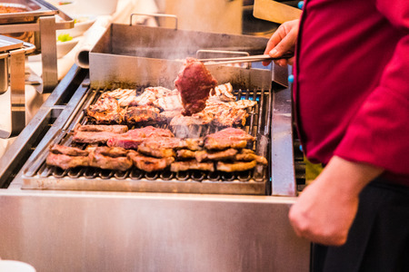 hands of a man preparing meat on the barbecue for a celebrationの写真素材