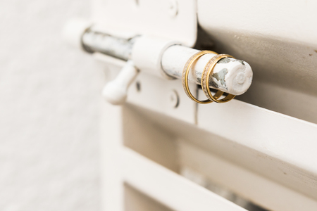 Two gold wedding rings on door lockwhite metalの写真素材