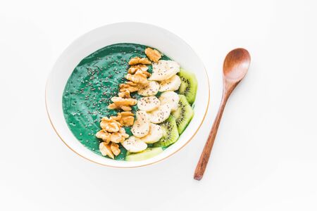 A spirulina smoothie bowl with banana, walnuts, kiwi and chia seeds on white backgroundの写真素材