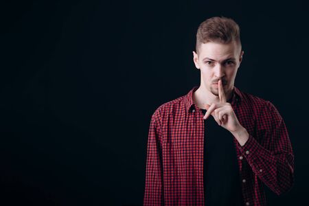 Young Man Touching His Lips in a Hush Gestureの写真素材