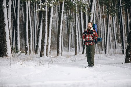 Smiling Bearded Hiker Enjoying Snowfall on Winter Forest Edgeの写真素材