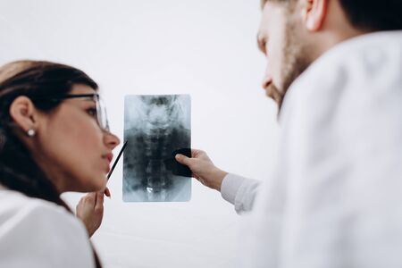 Physicians in White Coats Examining Spinal Radiography Image
