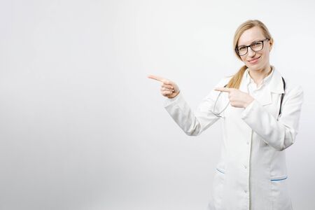Smiling female doctor pointing with fingers to copy spaceの写真素材