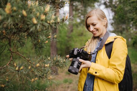 Happy woman reviewing taken photos on camera at forest