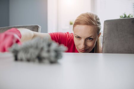 Close up of woman cleaning white kitchen table with brushの写真素材