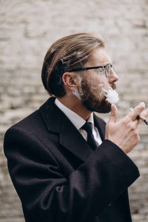 Bearded businessman smoking cigarette outdoors