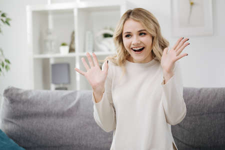 Amazed woman with open mouth sitting sofaの写真素材