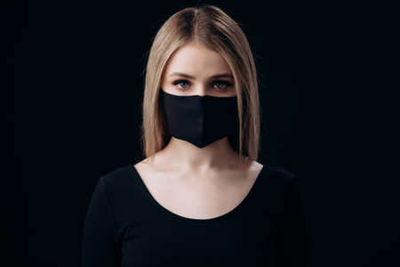 Woman in medical mask over black backgroundの写真素材