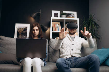 Young couple using laptop and VR headset at homeの写真素材