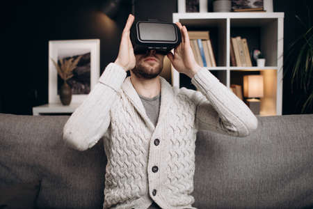Handsome man wearing VR headset at homeの写真素材