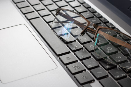 Laptop keyboard black on gray background with a glasses on it. Close-up of laptop keyboard.