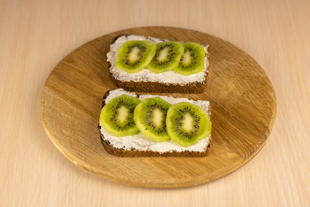 Rye bread spread with cream cheese with kiwi slices.の写真素材