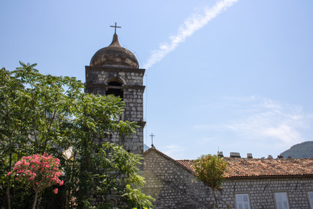Church towers visible against the backdrop of a mountain landscape and green trees. Old medieval church in backdrop of the mountains in Kotor Montenegro.の写真素材