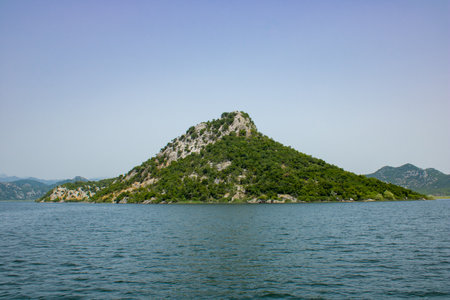 Landscape with lake and green mountains against the background of a clear sky. Panoramic beautiful view on largest lake. Wonderful summer day.の写真素材