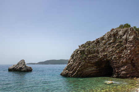 Rocky seaside coast. Boulders are standing in the beautiful water. Group of large stones against the blue sky. Big stone on the background of the sea.の写真素材