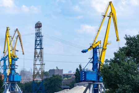 Big port cranes on the river. Extraction and transportation sand. Harbor crane loads water resources into barge. Special equipment and water transport. River port. Industrial city.の写真素材