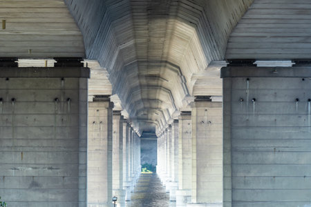 Tunnel from column under road bridge in city. Row pillar and group arches. Built structure...