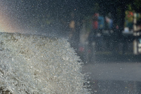 Movement transparent splash. Sparkling gush water of liquid drops detail. Fountain flows colors of rainbow in the city in sunny weather. Refreshing cool water on hot day. Sprays.の写真素材
