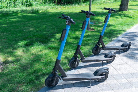 Electric scooter parked on sidewalk in city. Public mobile transport standing in pavement. Rent economical vehicle in contemporary urban. Business technology on rental. Ecological.の写真素材