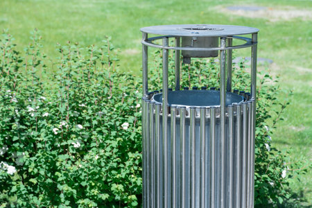 Stylish trash bin in the park. Modern garbage can for clean environment. Metal steel dustbin on city streets. Design dumpster outside. Cleanliness and tidiness in the garden.の写真素材