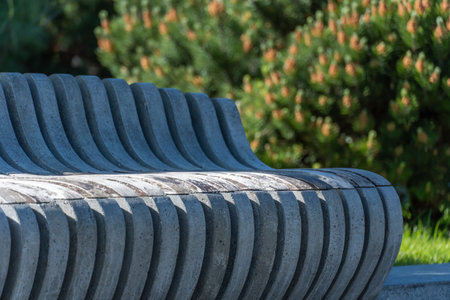 Comfortable wooden bench in city park. Design of brown stationary seat for leisure. Exterior empty park bench. Geometry on nature and place to rest. Furniture in parts material.の写真素材