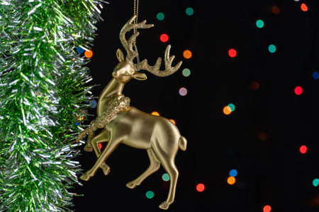 Close-up of beautiful Christmas tree toys deer on tinsel with flashing garland. Merry Christmas and...