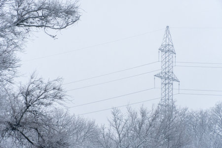 Electricity transmission towers and power lines in snow covered winter. High voltage pole on road. Energy concept of industry in countryside.の写真素材