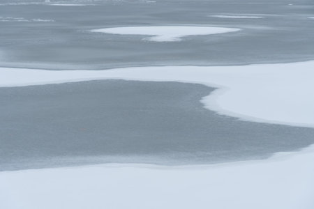 Melting of cold water and ice in river in early spring. Meltwater and white tones of ice contrast with the dark wave. Stream of snow in natural parkland.の写真素材