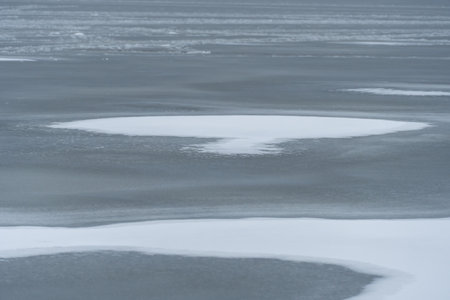 Melting of cold water and ice in river in early spring. Meltwater and white tones of ice contrast with the dark wave. Stream of snow in natural parkland.の写真素材