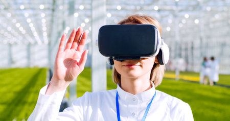 Portrait of smiling woman wearing virtual reality glasses working with agronomy scientific hologram...