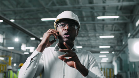 Busy hard-working African-American male talking on his modern phone. Man having lively discussion conversation. Engineer actively energetically gesticulating during phone call.の写真素材