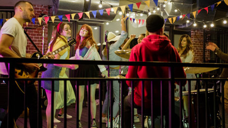 Beautiful young friends dancing on a rooftop concert, having fun and enjoying time together. Band with guitarist and drummer performing at a concert on party.の写真素材