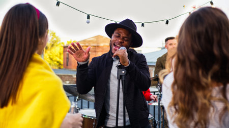 Band with guitarist, drummer and singer performing at a concert on party. Group of friends hanging...